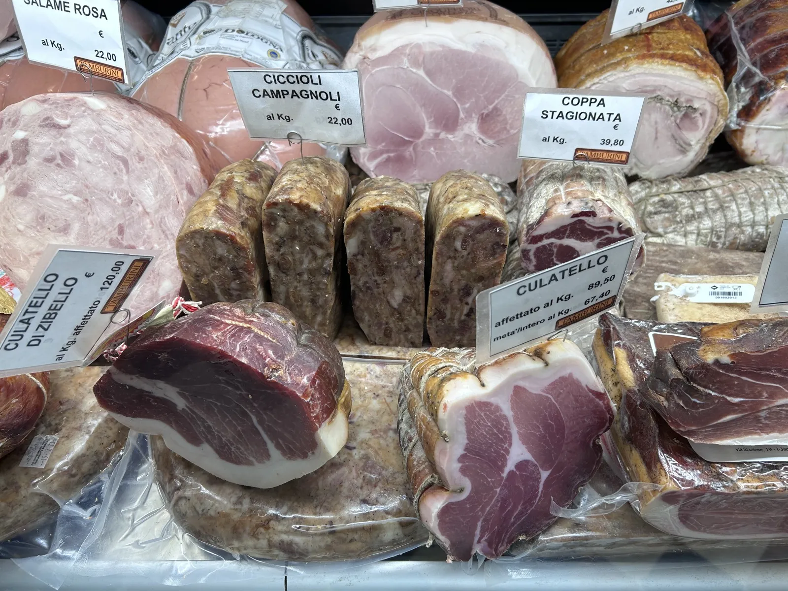 Fette di ciccioli, coppa e salumi tradizionali esposti su un bancone